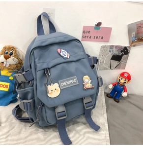 Détail du sac à dos en toile bleue avec des épingles de dessin animé et un porte-clés ours