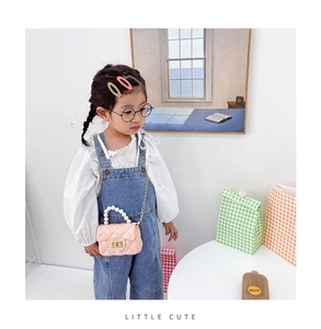 Close-up of pink mini quilted jelly bag with white pearl handle on a child model