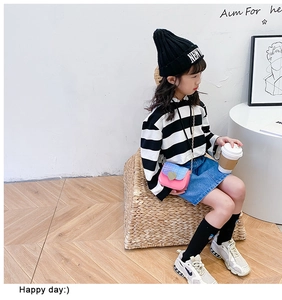 Détail du petit sac rose à chaîne avec cœur doré sur tenue rayée pour fille