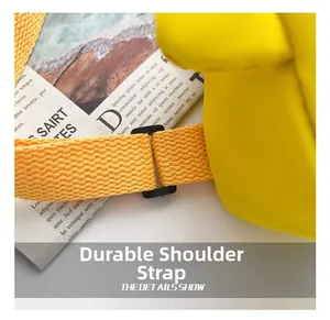 Detail of durable orange nylon shoulder strap with adjustable black plastic buckle on bag
