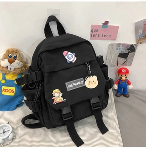Détails d'un sac à dos en nylon noir avec écussons décoratifs, étiquette et boucles latérales