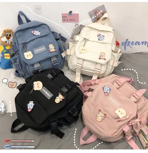 Détail de quatre mini sacs à dos en toile couleur macaron avec pins décoratifs