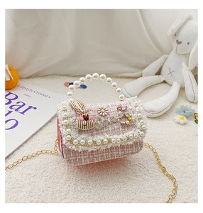 Detailed close-up of girls tweed crossbody bag with pearl handle and rhinestone patches