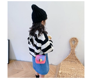 Sac bandoulière enfant avec boucle cœur et dégradé rose-bleu porté par un modèle