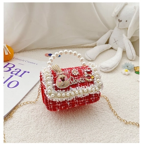 Detail of red tweed girls bag with pearl handle, rabbit decor and gold chain strap