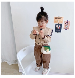 Détail d'une chemise beige à col marin et d'un pantalon marron pour petite fille