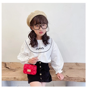 Detail of red quilted mini jelly bag with pearl handle and floral embroidery on shirt