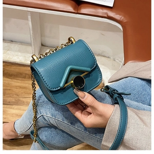 Dettaglio della mini borsa a tracolla verde pavone con catena dorata e fibbia in metallo a V
