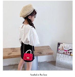 Detail of red quilted jelly bag with pearl handle and golden chain on a child model