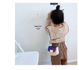 Vue de dos d'une fille portant un sac chaîne blanc crème avec rabat dégradé et fermoir cœur