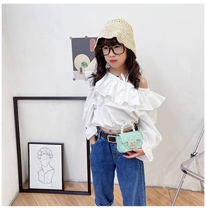 Girl wearing white ruffle blouse, jeans, and mint quilted pearl handle jelly handbag