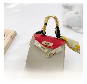 Dettaglio mini borsa rossa e bianca con manico in foulard di seta e chiusura dorata