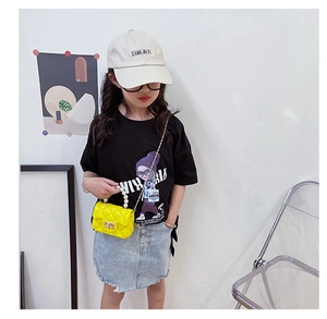 Close-up of girls yellow quilted mini bag with pearl handle and golden metal lock detail