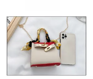 Mini borsa a trapezio con dettaglio in seta e confronto dimensioni con uno smartphone