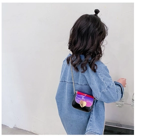 Détail d'une fille portant un sac en cuir noir et violet avec fermoir coeur doré et chaîne