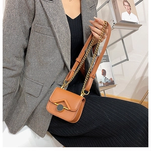 Dettaglio della mini borsa a tracolla in pelle marrone con catena dorata e cinturino