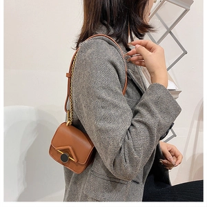 Dettaglio di una mini borsa a tracolla in pelle marrone con catena in metallo su modella