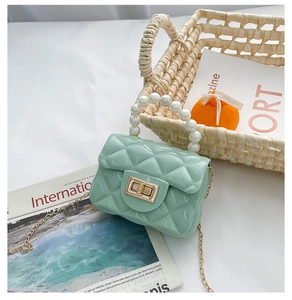 Detailed view of mint green jelly bag featuring pearl handle and gold twist lock