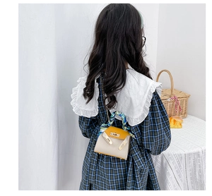 Dettaglio di una mini borsa per bambini con manico in seta e chiusura a girello d'oro