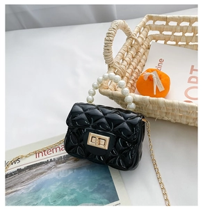 Detail of mini black quilted jelly bag with pearl handle and gold chain strap