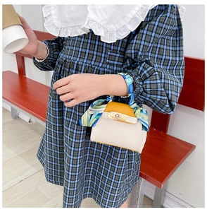 Dettaglio della mini borsa gialla e bianca stile Kelly con foulard in seta e fibbia oro
