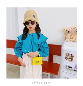 Detail of blue ruffled collar shirt and white skirt with yellow pearl handle bag