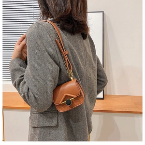Primo piano di una mini borsa a tracolla vintage marrone indossata da un bambino al chiuso