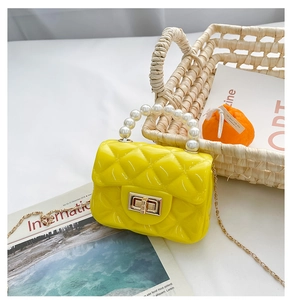 Close-up of bright yellow jelly purse with quilted pattern, pearl handle and gold chain