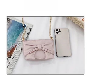 Detailed view of pink bow purse with gold chain strap next to a smartphone