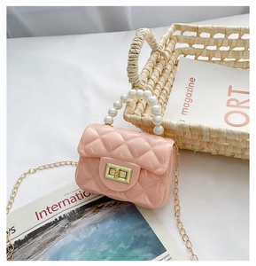 Detail of pink jelly crossbody bag with quilted pattern, pearl handle, and gold chain strap
