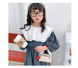 Dettaglio outfit bimba con vestito a quadri e mini borsa a mano con foulard di seta