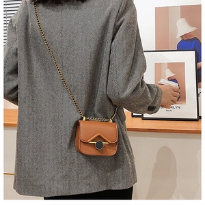Ragazza con mini borsa vintage marrone e tracolla a catena dorata spessa sulla spalla