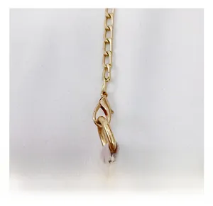 Close-up of golden lobster clasp and metallic chain on a light pink girls handbag