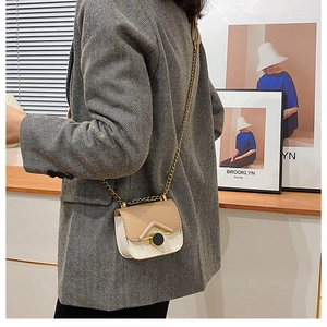 Mini borsa a tracolla bicolore beige con catena dorata indossata dal modello