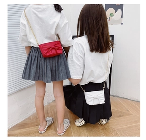 Kids mini crossbody bags with bow detail and gold chain straps shown on young models