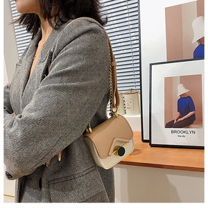 Dettaglio di una mini borsa a tracolla bicolore con catena in metallo e chiusura dorata