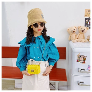 Girl wearing a stylish peacock blue puff sleeve top with a mini yellow pearl chain bag