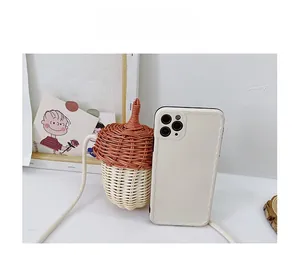 Size comparison of acorn-shaped woven crossbody bag next to a smartphone device