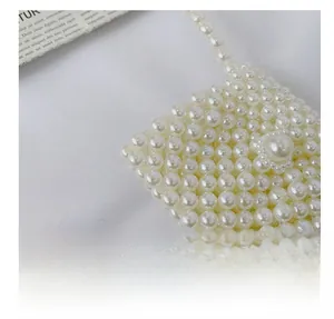 Close-up of handmade cream faux pearl woven crossbody bag with detailed bead texture