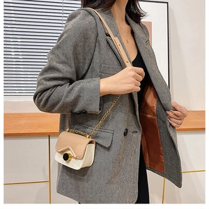 Dettaglio di una mini borsa a catena color-block in pelle beige e kaki su un modello