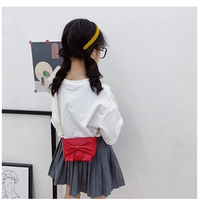 Detail view of red girls crossbody bag with large bow and gold metal chain strap