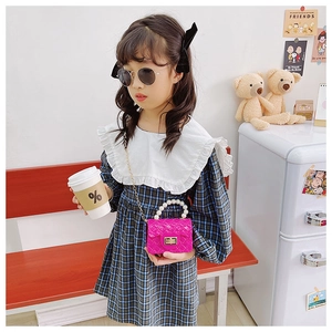 Detail of kids pink jelly bag with pearl handle and golden chain on a young girl