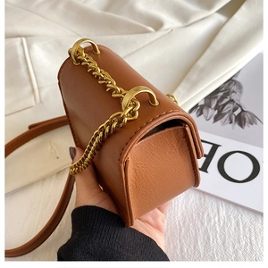 Dettaglio mini borsa a tracolla marrone con catena dorata e cinturino in pelle su tessuto