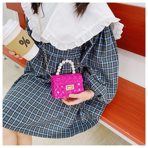 Detail of rose red jelly bag with pearl handle, golden chain, and woven texture