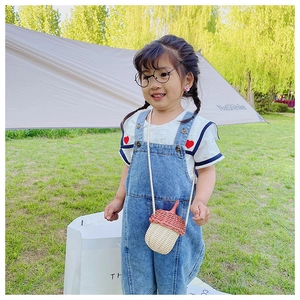 Close-up of a mini acorn-shaped woven crossbody bag for kids shown in an outdoor setting