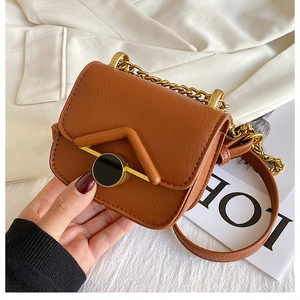 Dettaglio mini borsa a tracolla in pelle marrone con catena dorata e fibbia tonda in metallo