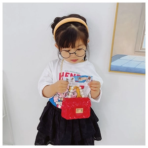 Detailed macro of kids red jelly handbag with pearl handle and golden chain strap