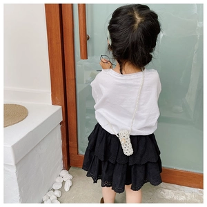 Rear view of a child wearing a white pearl beaded mini crossbody bag with a long strap