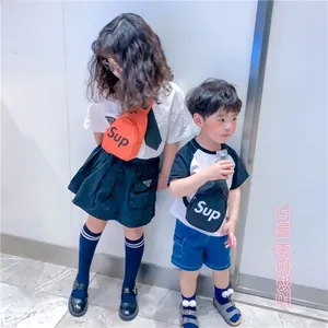 Détail de la sacoche mode pour enfants avec logo métallique et bandoulière réglable