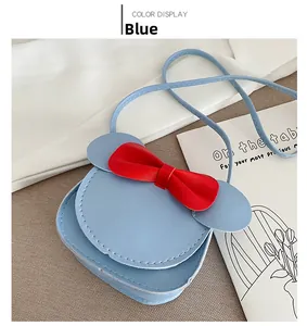 Detail view of mini blue kids crossbody bag with red bow and cute ears cartoon design